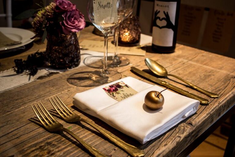 Gedeckter Holztisch mit Serviette, Goldbesteck und Kerzen